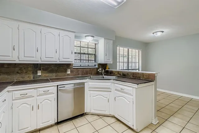 a kitchen with white cabinets appliances a sink and a window