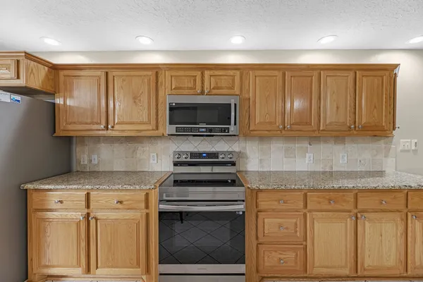 a kitchen with stainless steel appliances granite countertop a stove a sink and a microwave