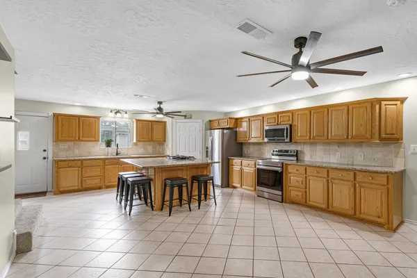 a view of a refrigerator in kitchen and an empty room in wooden floor