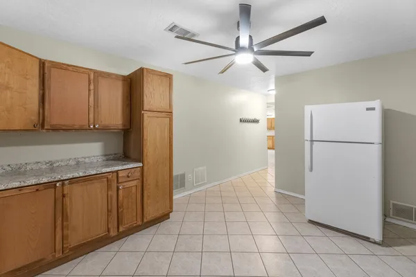 an empty room with chandelier fan and windows