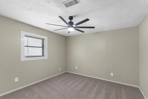 an empty room with closet and a ceiling fan