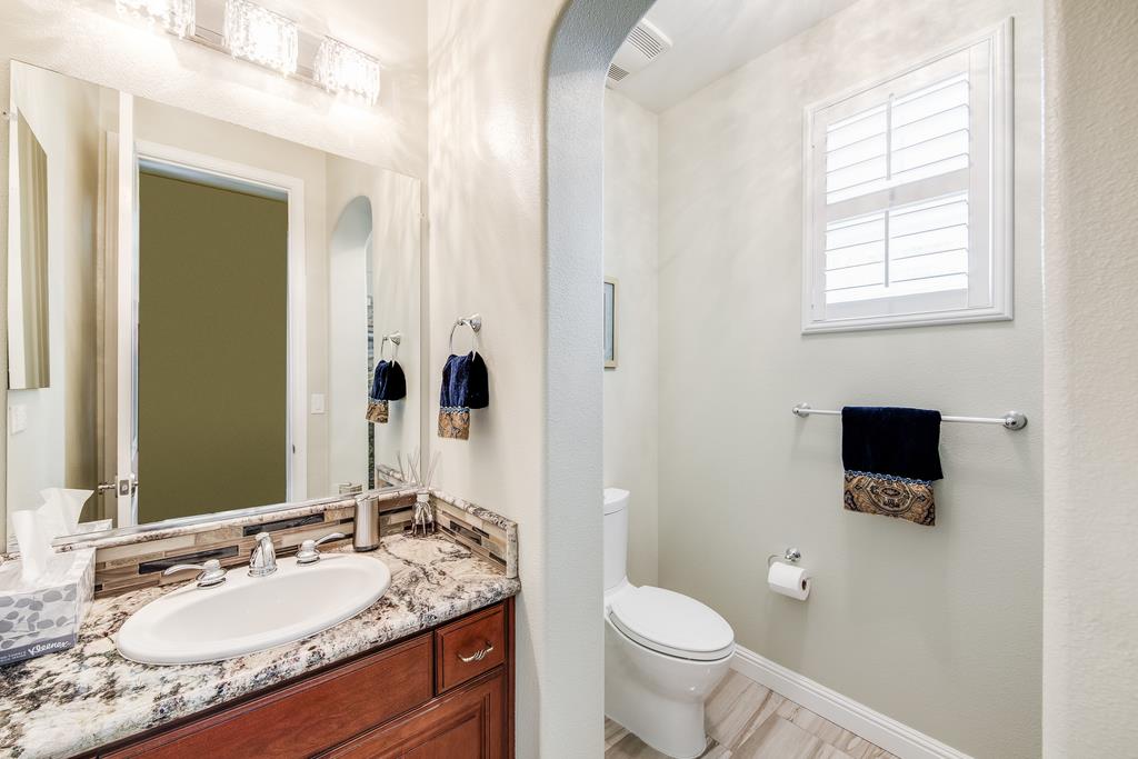 7670 MacKenzie Way Gilroy, CA 95020 - Photo 35 of 70 a bathroom with a granite countertop toilet a sink and a mirror