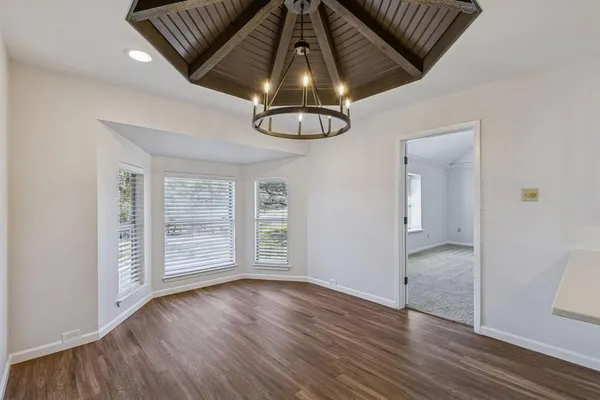 an empty room with wooden floor cabinet and windows