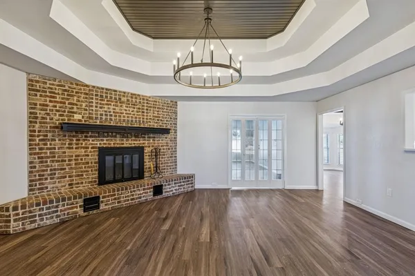 a view of an empty room with wooden floor fireplace and a window