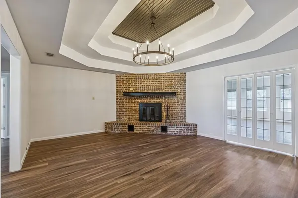 a view of an empty room with a fireplace and a chandelier
