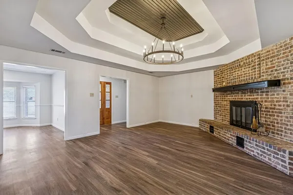 a view of empty room with wooden floor and kitchen view