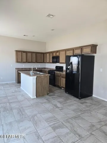 a room with stainless steel appliances granite countertop a stove a sink dishwasher and a refrigerator