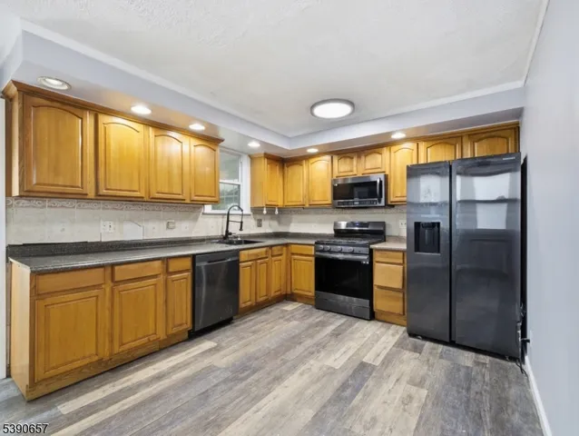 a kitchen with granite countertop stainless steel appliances a refrigerator cabinets and a sink