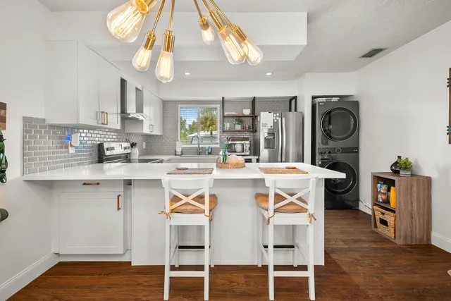 a kitchen with stainless steel appliances kitchen island granite countertop a refrigerator a stove a sink dishwasher and a dining table with wooden floor