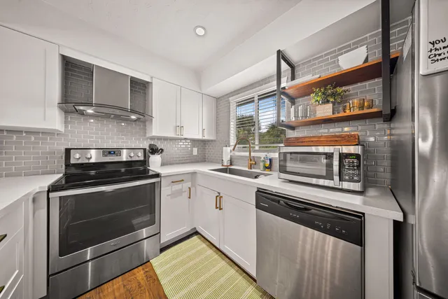 a kitchen with stainless steel appliances a stove a refrigerator and a microwave