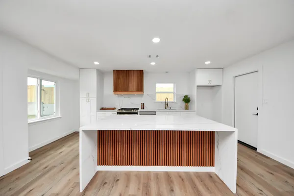 a large kitchen with kitchen island a sink wooden floor and glass door