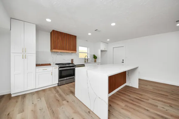 a kitchen with stainless steel appliances white cabinets and wooden floor