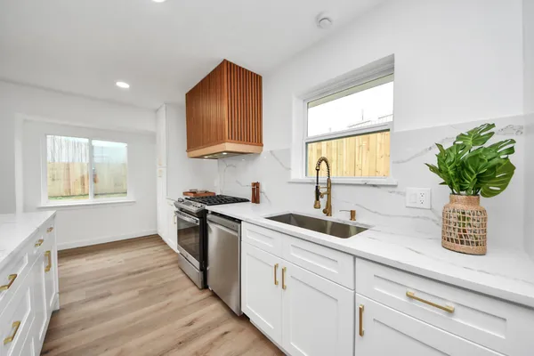 a kitchen with stainless steel appliances granite countertop a sink a stove and a window