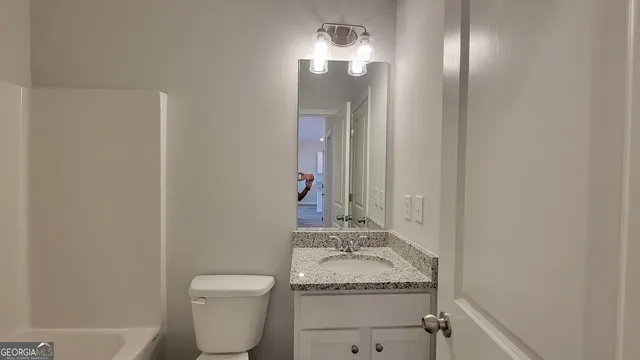 a bathroom with a granite countertop sink toilet and a mirror