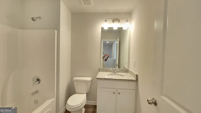 a bathroom with a granite countertop sink a toilet and shower