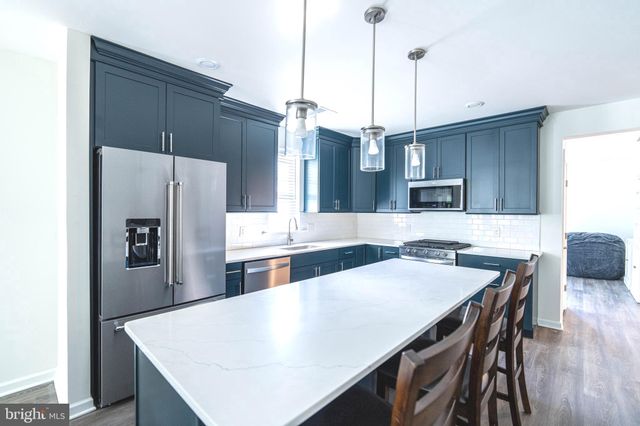 a kitchen with stainless steel appliances a refrigerator a sink a stove and a center island