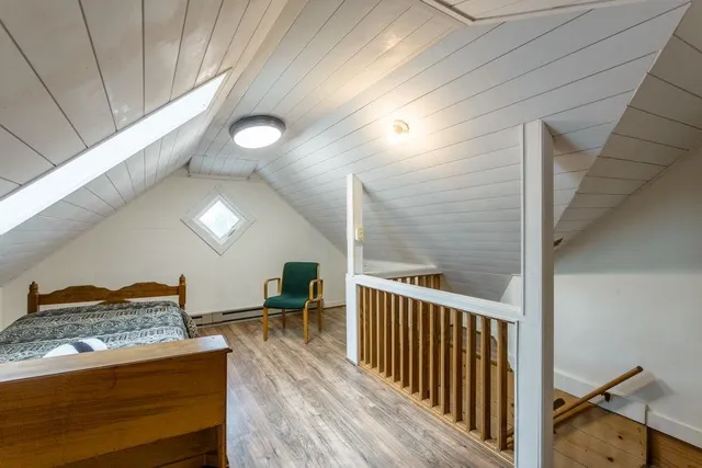 a view of an empty room with wooden floor and windows