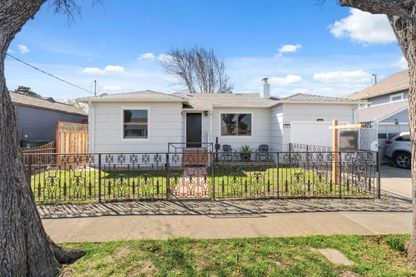 a view of a house with a small yard and wooden fence