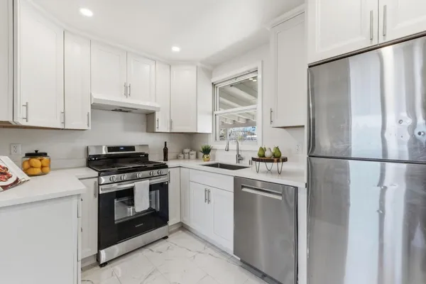 a kitchen with a refrigerator a sink dishwasher a dining table and chairs