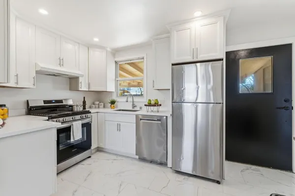 a kitchen with granite countertop a stove a sink a dining table and chairs