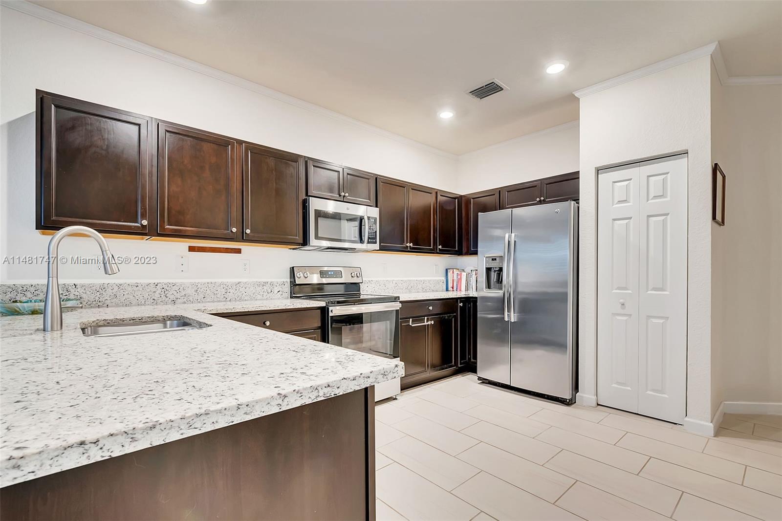 15073 Southwest 119TH Lane Miami, FL 33196 - Photo 13 of 25 a kitchen with granite countertop a refrigerator and a stove top oven