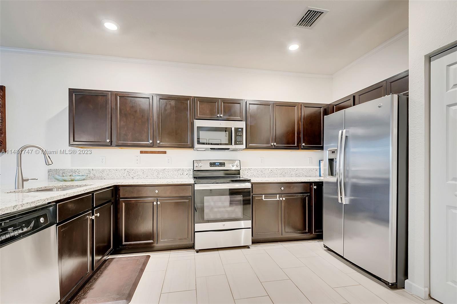 15073 Southwest 119TH Lane Miami, FL 33196 - Photo 3 of 25 a kitchen with stainless steel appliances granite countertop a stove a sink and a refrigerator
