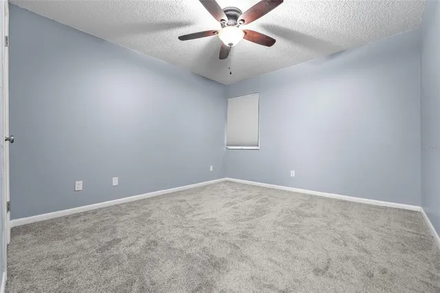 a view of an empty room and chandelier fan