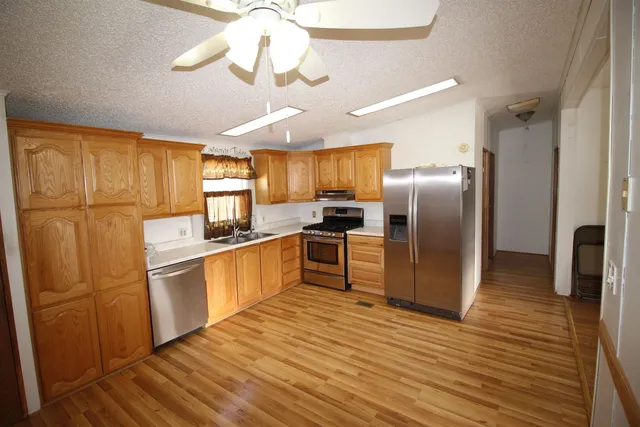 a kitchen with granite countertop stainless steel appliances a refrigerator a stove top oven a sink and cabinets