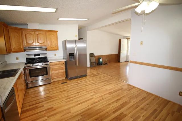 a kitchen with stainless steel appliances a refrigerator and wooden floor