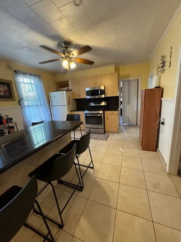 a kitchen with stainless steel appliances kitchen island granite countertop a refrigerator a stove a microwave oven and a dining table with wooden floor