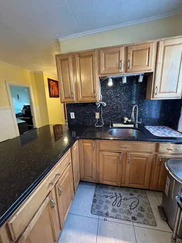 a kitchen with granite countertop a sink a stove top oven a granite counter space and cabinets