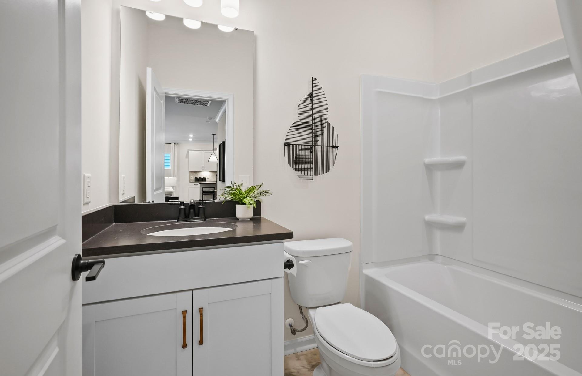 12016 Rails Court, Unit 516 Charlotte, NC 28278 - Photo 19 of 39 a bathroom with a granite countertop sink a toilet a mirror and bathtub