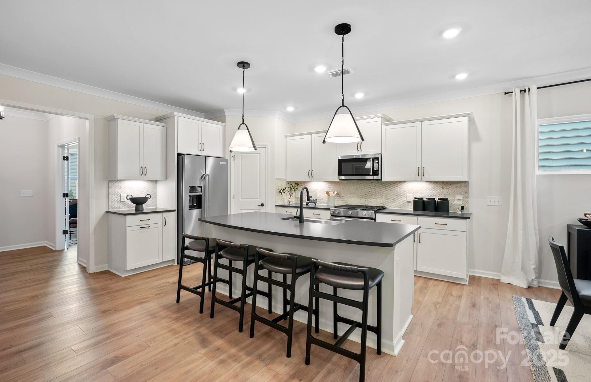 12016 Rails Court, Unit 516 Charlotte, NC 28278 - Photo 10 of 39 a kitchen with stainless steel appliances granite countertop a stove a sink a refrigerator and chairs with wooden floor