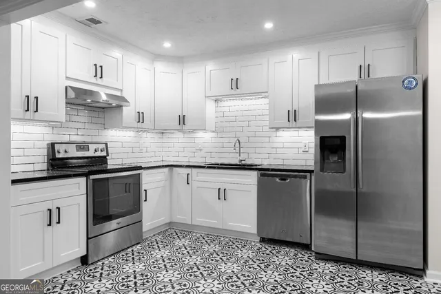 a kitchen with granite countertop white cabinets and stainless steel appliances