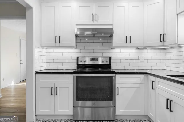 a kitchen with granite countertop white cabinets and stainless steel appliances