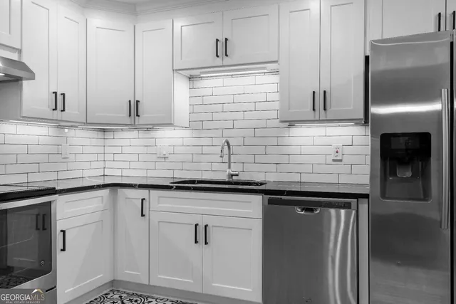 a kitchen with stainless steel appliances granite countertop a refrigerator a stove and white cabinets