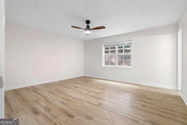a view of empty room with wooden floor and ceiling fan