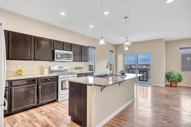 a kitchen with kitchen island granite countertop a sink cabinets and wooden floor