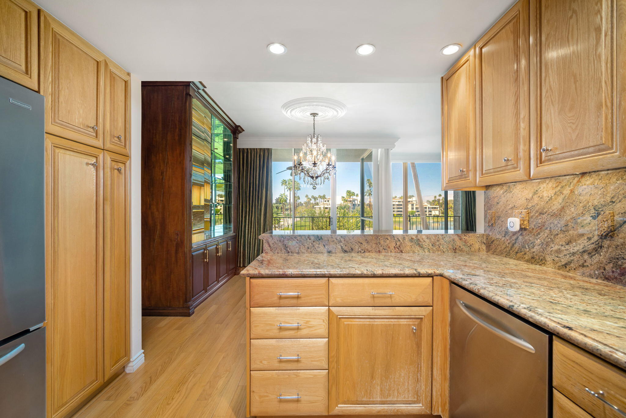 900 Island Drive, Unit 304 Rancho Mirage, CA 92270 - Photo 18 of 27 a kitchen with kitchen island granite countertop wooden cabinets and white appliances