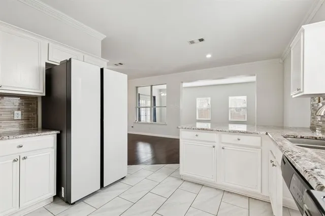 a kitchen with white cabinets and refrigerator