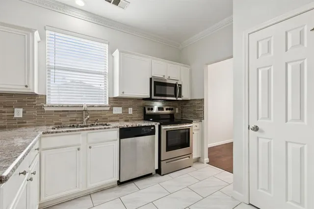 a kitchen with white cabinets and appliances