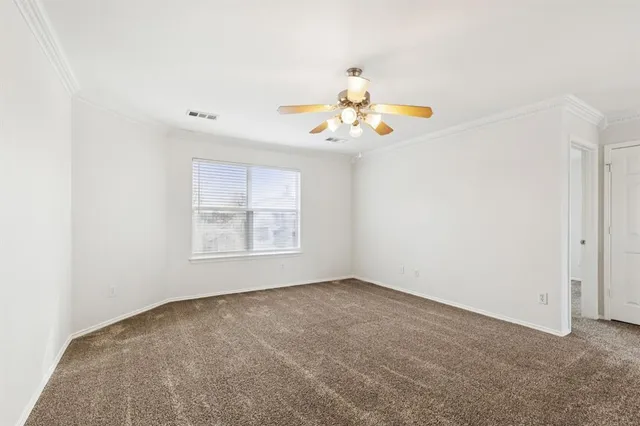 an empty room with windows and chandelier fan