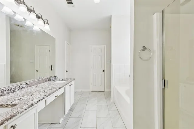 a spacious bathroom with a granite countertop sink a mirror and shower