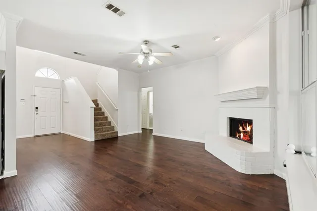 a view of an empty room with wooden floor and a ceiling fan