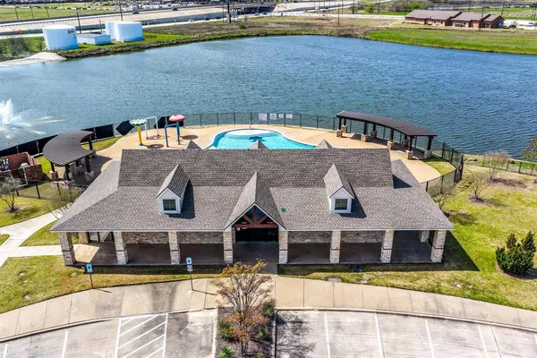 a view of a swimming pool with lawn chairs and large trees