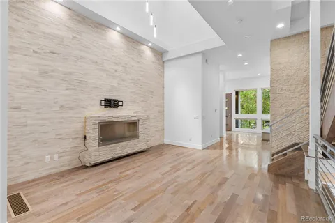 a hallway with wooden floor a fireplace and a window