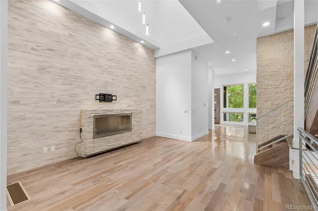 a hallway with wooden floor a fireplace and a window