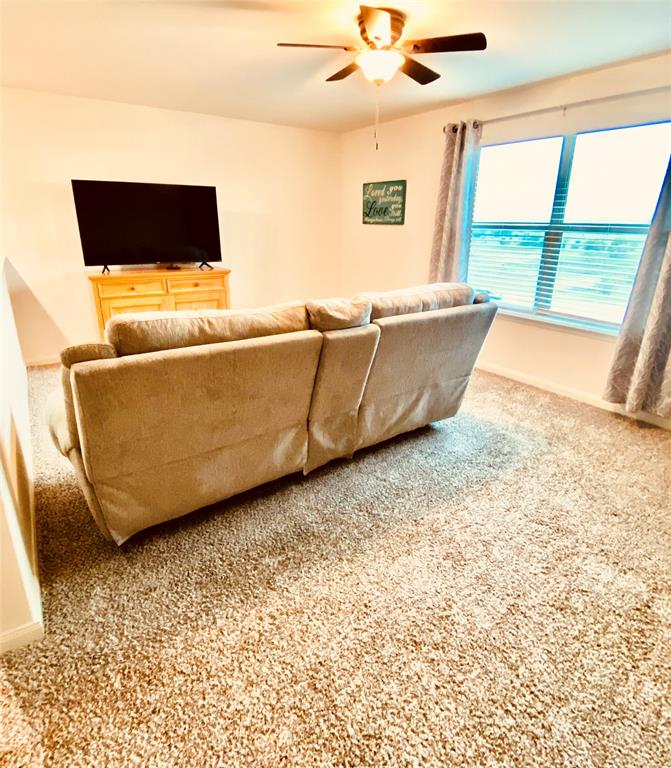 196 Cattlemans Crk Road West Newark, TX 76071 - Photo 11 of 24 Carpeted room featuring a ceiling fan with integrated lighting, a large window, and light-toned wall finishes
