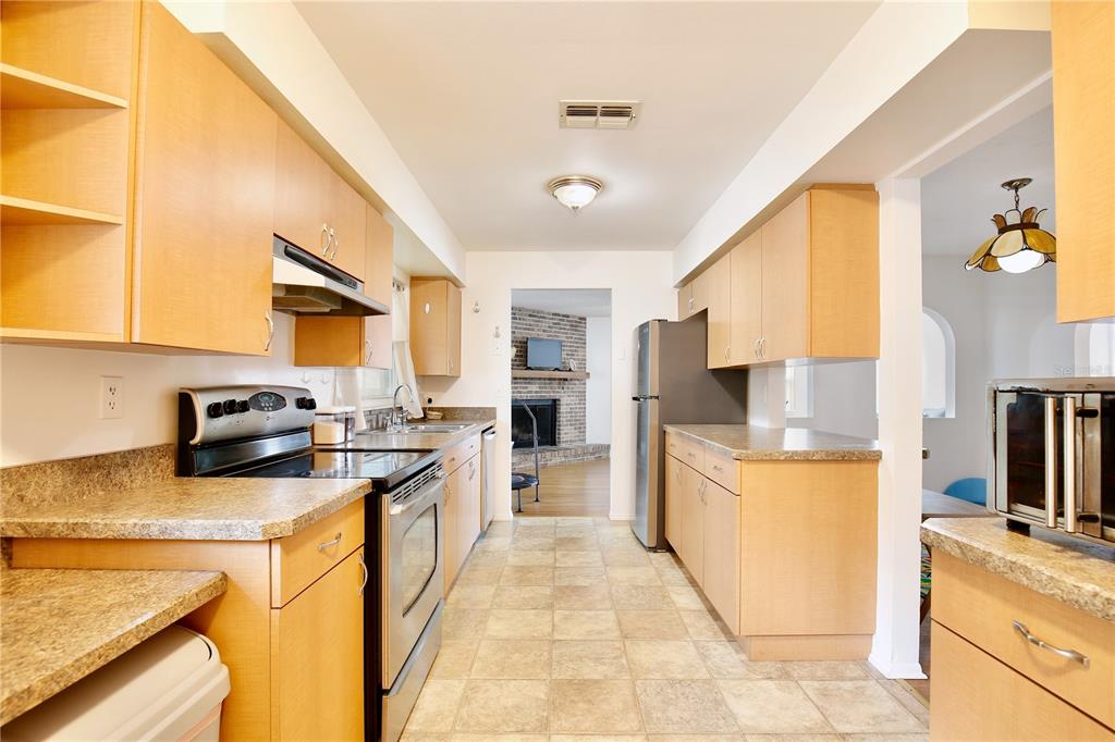 1179 Shadow Run Drive Lakeland, FL 33813 - Photo 10 of 42 a kitchen with stainless steel appliances granite countertop a stove top oven a sink a refrigerator white cabinets and wooden floor
