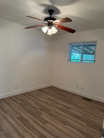 a view of wooden floor and chandelier fan in a room